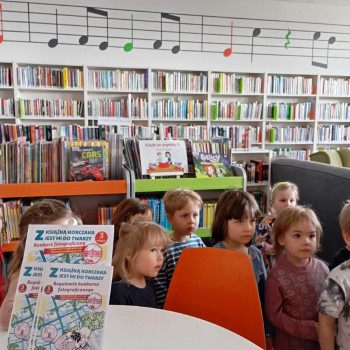 Dzieci w sali w bibliotece.
Z tyłu regały z książkami.