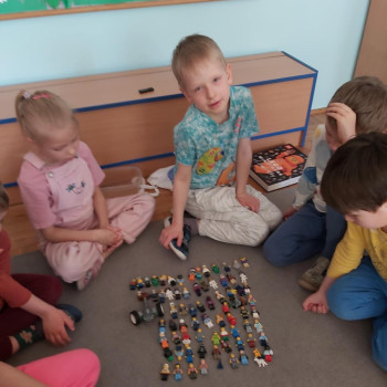 Chłopiec pokazuje figurki - klocki lego. Dzieci się przyglądają.