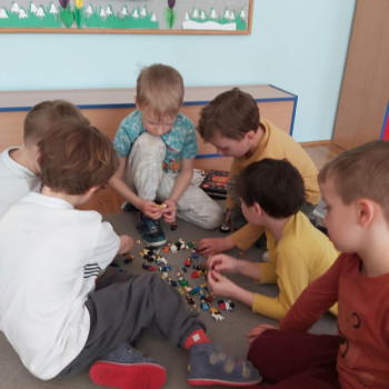 Dzieci na podłodze w sali bawią się figurkami klocków lego