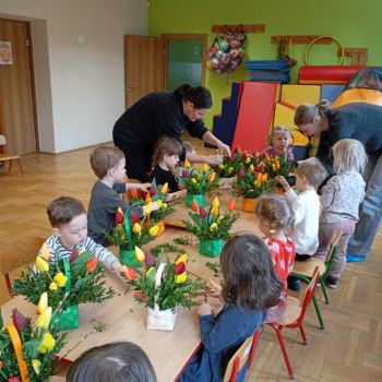 Dzieci wkładają kwiaty do koszyczków.