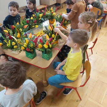 Dzieci dfokładaja do koszyczków kolorowe tulipany.